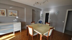 A dining area with a table, chairs, a white cabinet, and two wall-mounted pictures. - Studio in Knokke-Heist near the Beach (KNOKKE-HEIST)