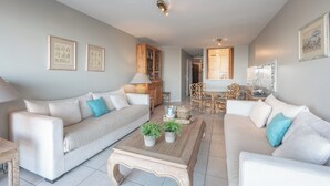 Una sala de estar moderna con dos sofás, una mesa de centro y un comedor con mesa y sillas.