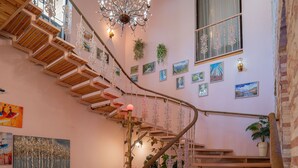 A wooden staircase with a chandelier, artwork on the walls, and a potted plant. - Hotel and Restaurant VILLA GIVISI (Lagodekhi)
