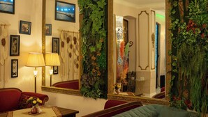 A living room with a green sofa, red armchair, chandelier, and a large mirror with a gold frame. - Hotel and Restaurant VILLA GIVISI (Lagodekhi)