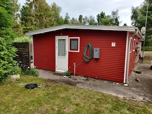 A red single-story building with a white door, a small window, and a number '7' on the side. - Charming holiday home in peaceful surroundings (Gedser)