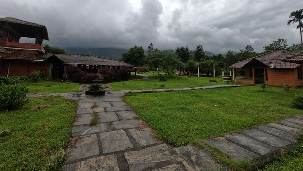 A courtyard with stone pathways, surrounded by traditional buildings with tiled roofs. - Jungle Mount Adventures (Madikeri)