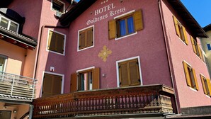 A pink building with the sign "HOTEL Goldenes Kreuz" and a balcony with a wooden railing. - Hotel Goldenes Kreuz (Vipiteno)