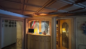A room with a wooden ceiling, a glass display case with various items, and a door leading to another room. - Hotel Goldenes Kreuz (Vipiteno)