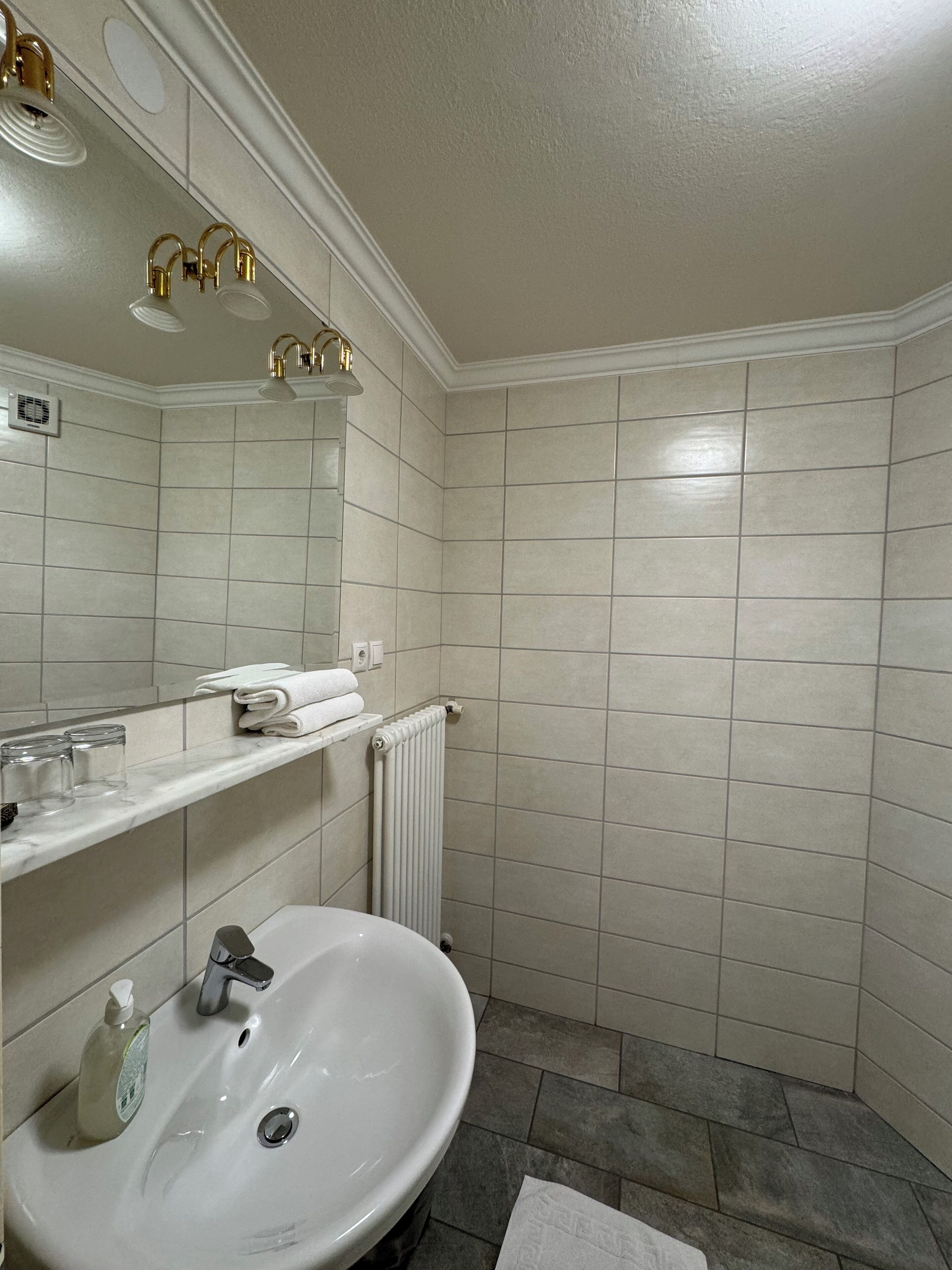 A bathroom with a white sink, a mirror, and a shower area.