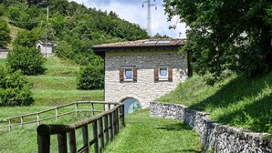 A stone building with a sloped roof, a wooden fence, and a stone wall.