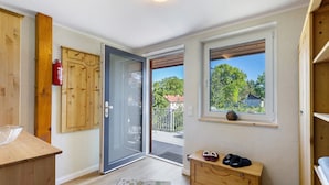 A room with wooden cabinets, a sliding glass door to a balcony, a small wooden dresser, and a window with a view of trees and buildings.