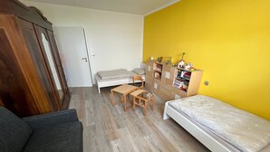 Ein kleines Zimmer mit einem Bett, einem Schreibtisch, einem Stuhl, einem Kleiderschrank und einem Bücherregal.