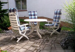 A patio with a round table and four chairs, each with a plaid cushion. - Apartment 'Am Silberg' with Mountain View, Private Terrace, and Wi-Fi (Plettenberg)