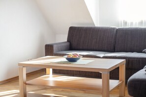 Un salon moderne avec une table basse en bois, un saladier de fruits et un canapé gris.