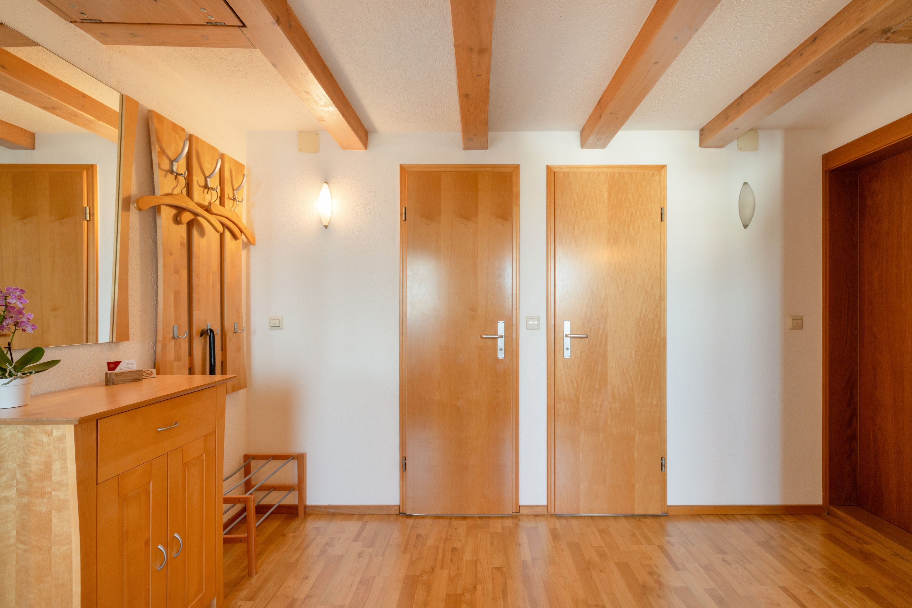 Une pièce avec un plancher en bois, un banc en bois, une armoire en bois dotée de tiroirs et un luminaire fixé au mur.