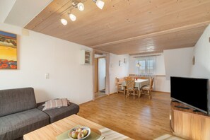 Un salon comprenant un canapé, une table à manger avec des chaises, un téléviseur et un tableau accroché au mur.