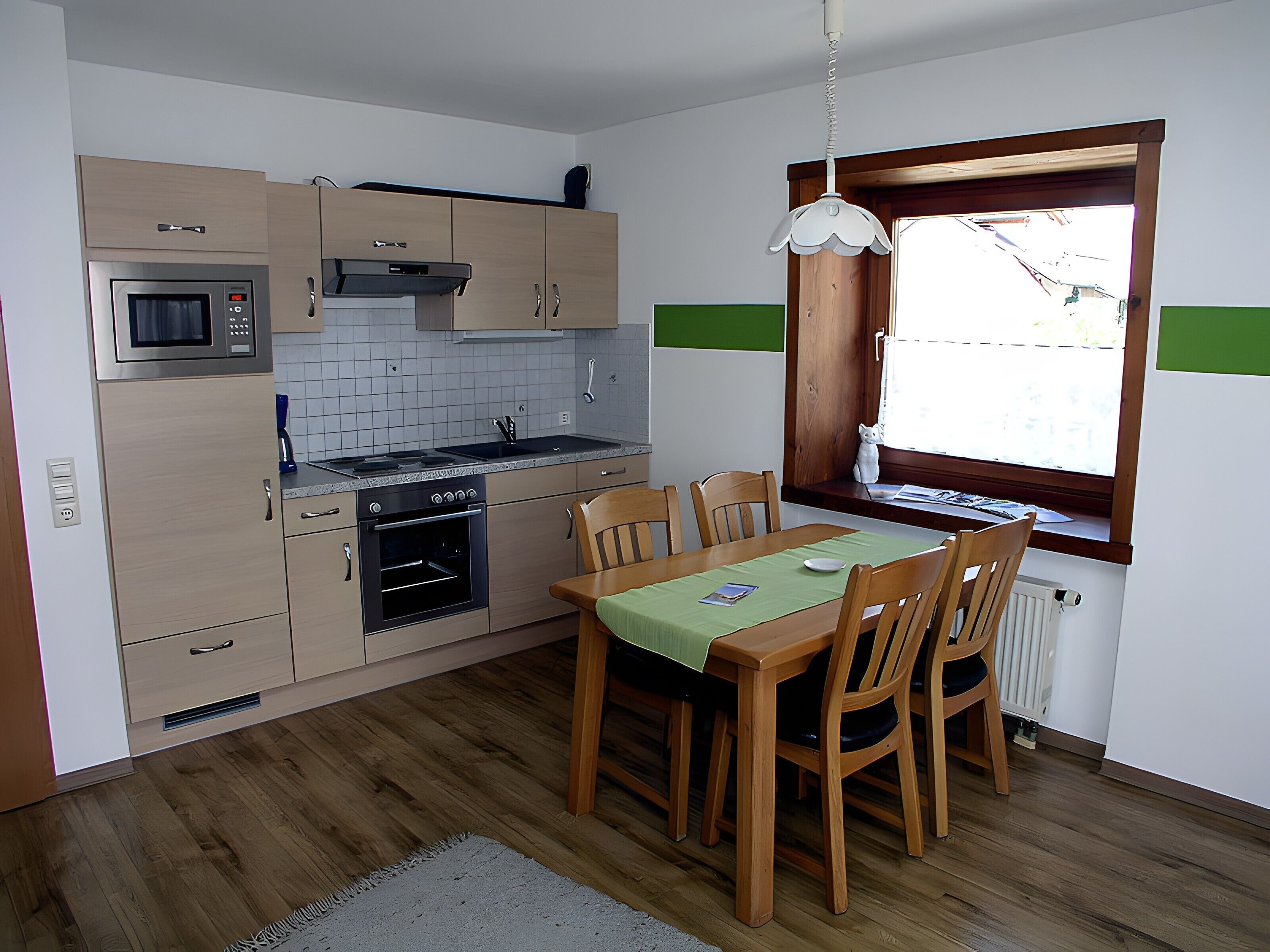 Une cuisine compacte dotée d’appareils électroménagers modernes, une table à manger avec des chaises et une fenêtre offrant une belle vue.