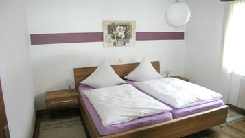 Ein Schlafzimmer mit einem hölzernen Bett, zwei Nachttischen, einem Wandleuchter, einem Gemälde und einem Fenster mit Vorhängen.
