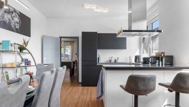 Une cuisine moderne dotée d’un îlot central, de tabourets de bar et d’un coin repas avec une table et des chaises.