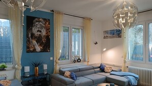 Un salon moderne avec un canapé d’angle, une table basse et une grande fenêtre agrémentée de rideaux.