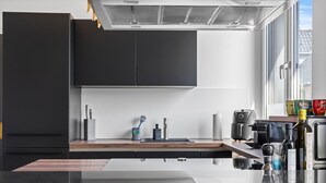 Une cuisine moderne dotée d’un plan de travail noir, d’appareils électroménagers en acier inoxydable et d’une fenêtre laissant entrer la lumière naturelle.
