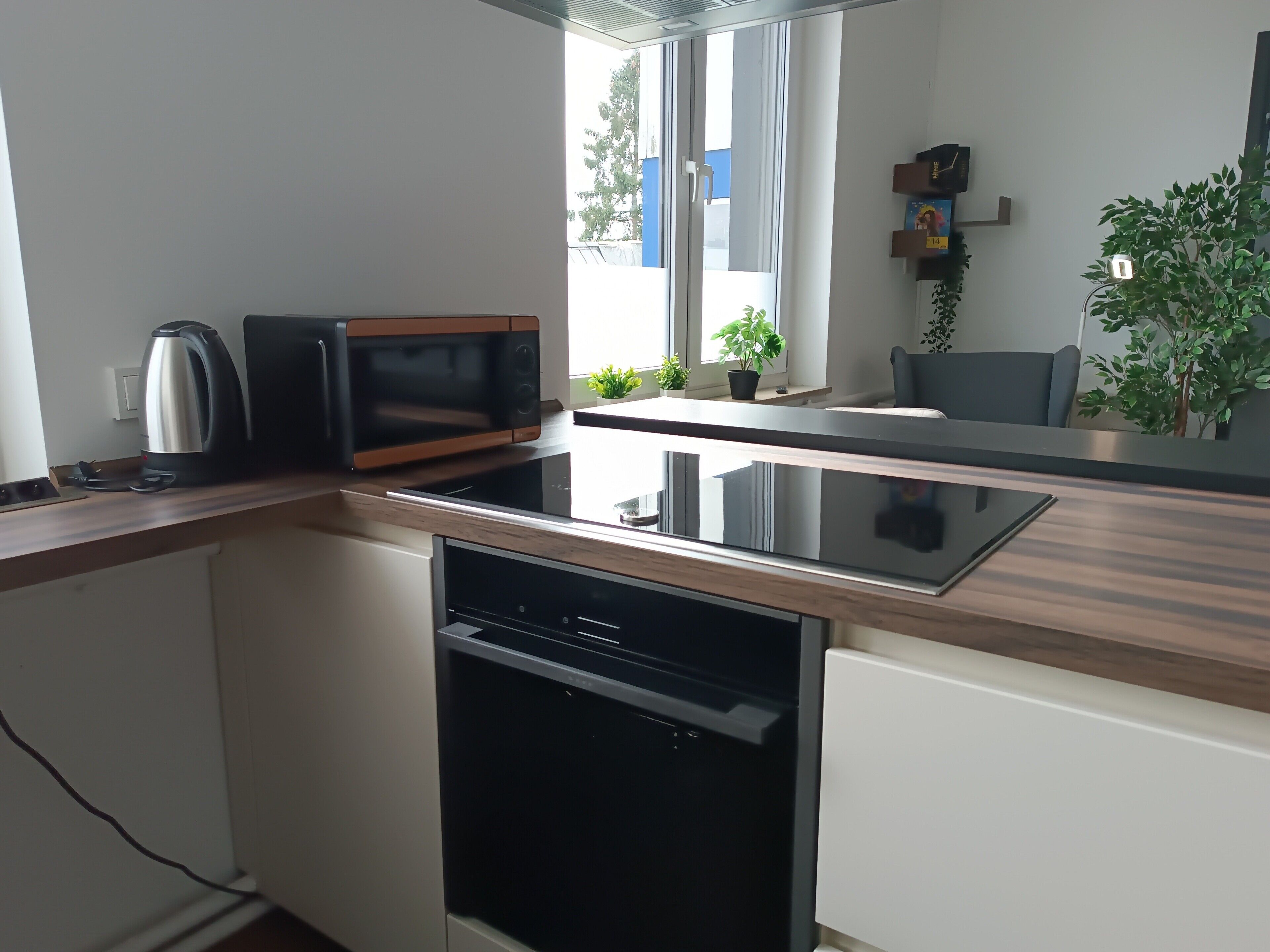 Una cucina moderna con microonde, bollitore, lavastoviglie e una finestra vista esterna.