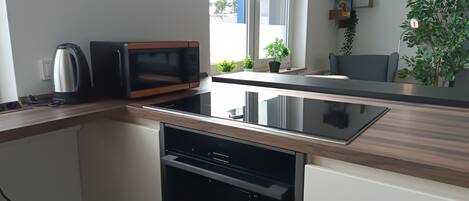 Una cucina moderna con microonde, bollitore, lavastoviglie e una finestra vista esterna.