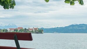 A bench by a lake with a distant view of a castle and mountains.