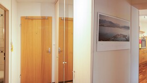 A hallway with wooden doors, a vent, and a poster on the wall.