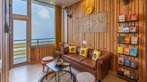 A cozy living room with a leather sofa, a coffee table, and a bookshelf filled with books. - The Hosteller Kufri, Shimla (Theog)