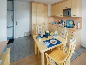 Una cocina funcional con armarios de madera, microondas y un comedor con mesa y sillas.