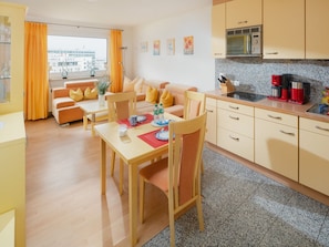 A modern apartment with a dining area, kitchen, and living room. - Apartment 'Terracotta' with Balcony and Wi-Fi (Norderney)