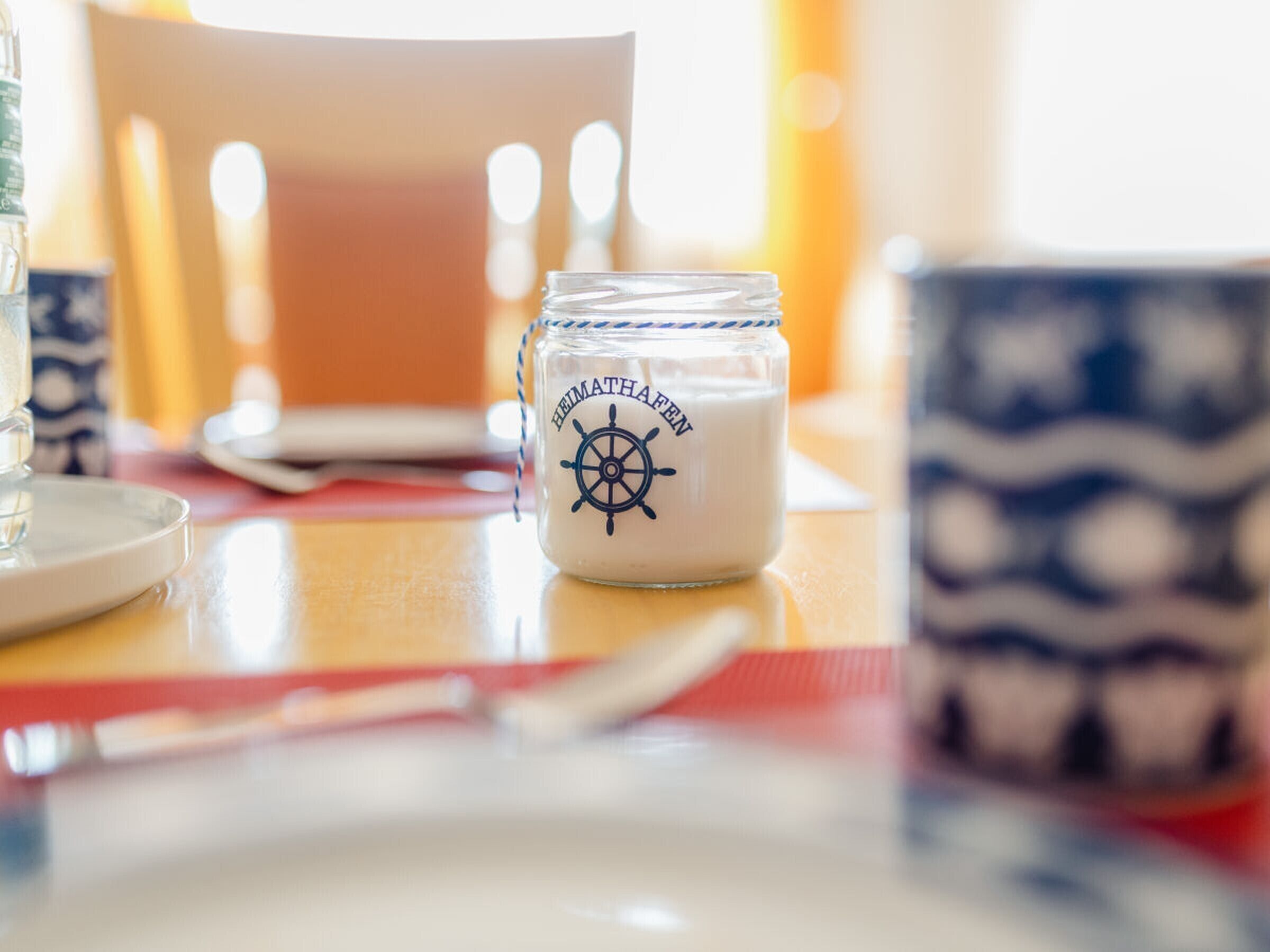 Une table sur laquelle se trouve un bocal étiqueté « HELMATHAFEN » et une tasse bleue et blanche à motifs.