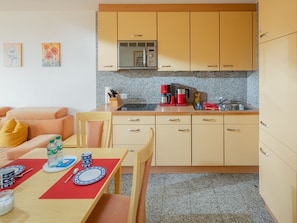 Una cocina compacta con encimera de granito, cafetera y lavamanos.