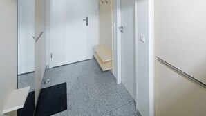 A narrow hallway with a door, a small step, and a doormat.