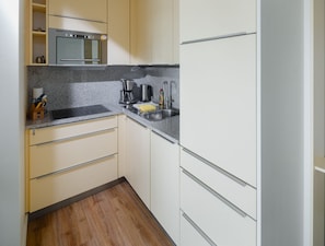 Una cocina con horno empotrado, cafetera, pileta y piso de madera.