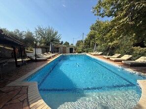 A rectangular swimming pool with clear blue water, surrounded by lounge chairs and a stone deck. - Makis House (Sithonia)