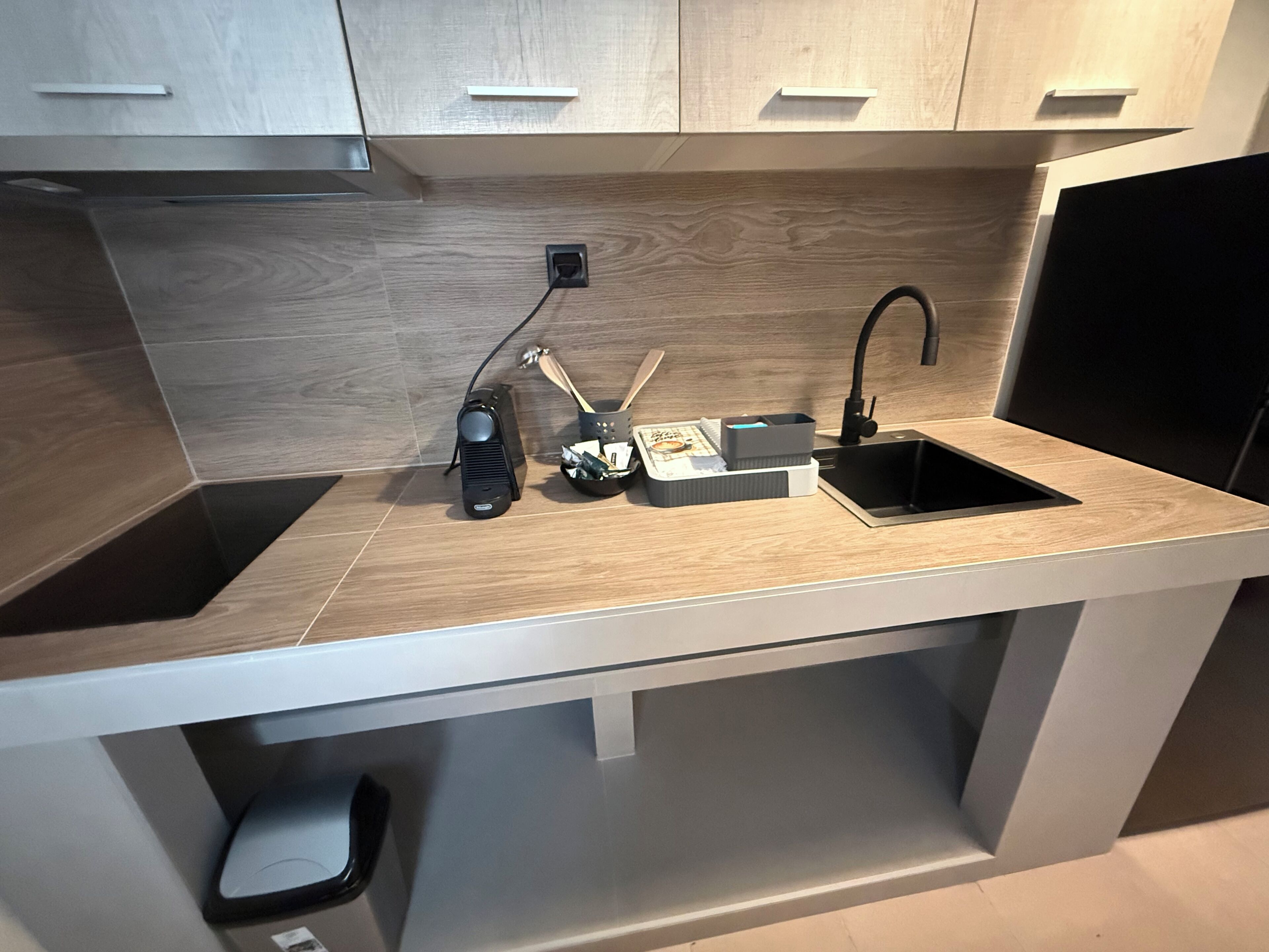 A modern kitchen with a built-in sink, a stove, and a countertop with a coffee machine and utensils.