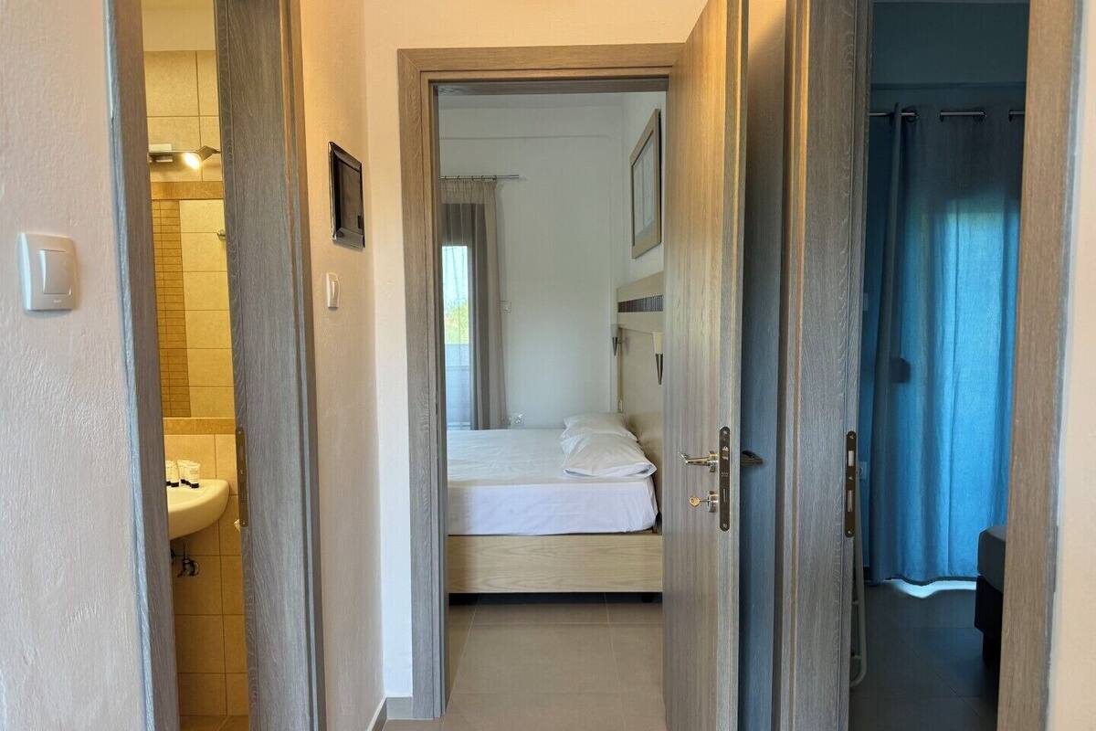 Una habitación de hotel con una cama, un baño con lavamanos y una zona de ducha.