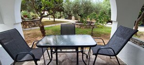 An outdoor patio with a table and two chairs, surrounded by stone walls and greenery. - Makis House (Sithonia)