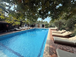 Una piscina al aire libre, sillones reclinables de piscina
