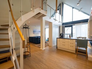 Uma sala de estar ampla com escada, cozinha e área de jantar.