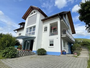 Une maison à deux étages avec un balcon, un garage et une allée pavée.