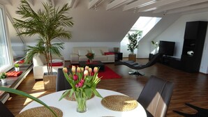 A modern living room with a round white table, black chairs, a large potted plant, and a sofa. - Apartment 'Bodenseeblick' with Lake View, Balcony and Wi-Fi (Nonnenhorn)