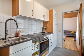 A modern kitchen with a stainless steel sink, oven, and built-in cabinets.