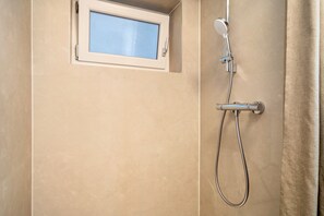 A bathroom with a shower, a window, and a curtain.
