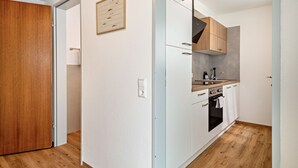 Une cuisine moderne avec des meubles blancs, une porte en bois et un interrupteur sur le mur.