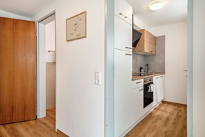 A modern kitchen with white cabinets, a wooden door, and a light switch on the wall.