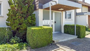 Un immeuble résidentiel moderne doté d’un jardin bien entretenu, d’une boîte aux lettres et d’une porte portant le numéro 33.