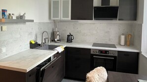 Una cocina moderna con una isla central, armarios oscuros y un horno empotrado.