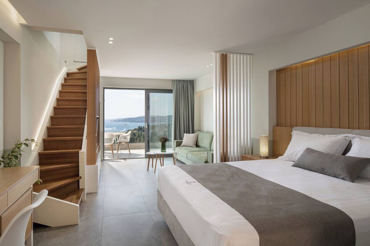 A modern bedroom with a large bed, a wooden staircase, a balcony with a view, and a minimalist design.