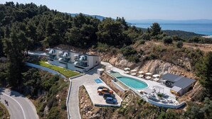 Un resort moderno con piscina, mobiliario exterior y vistas al mar.