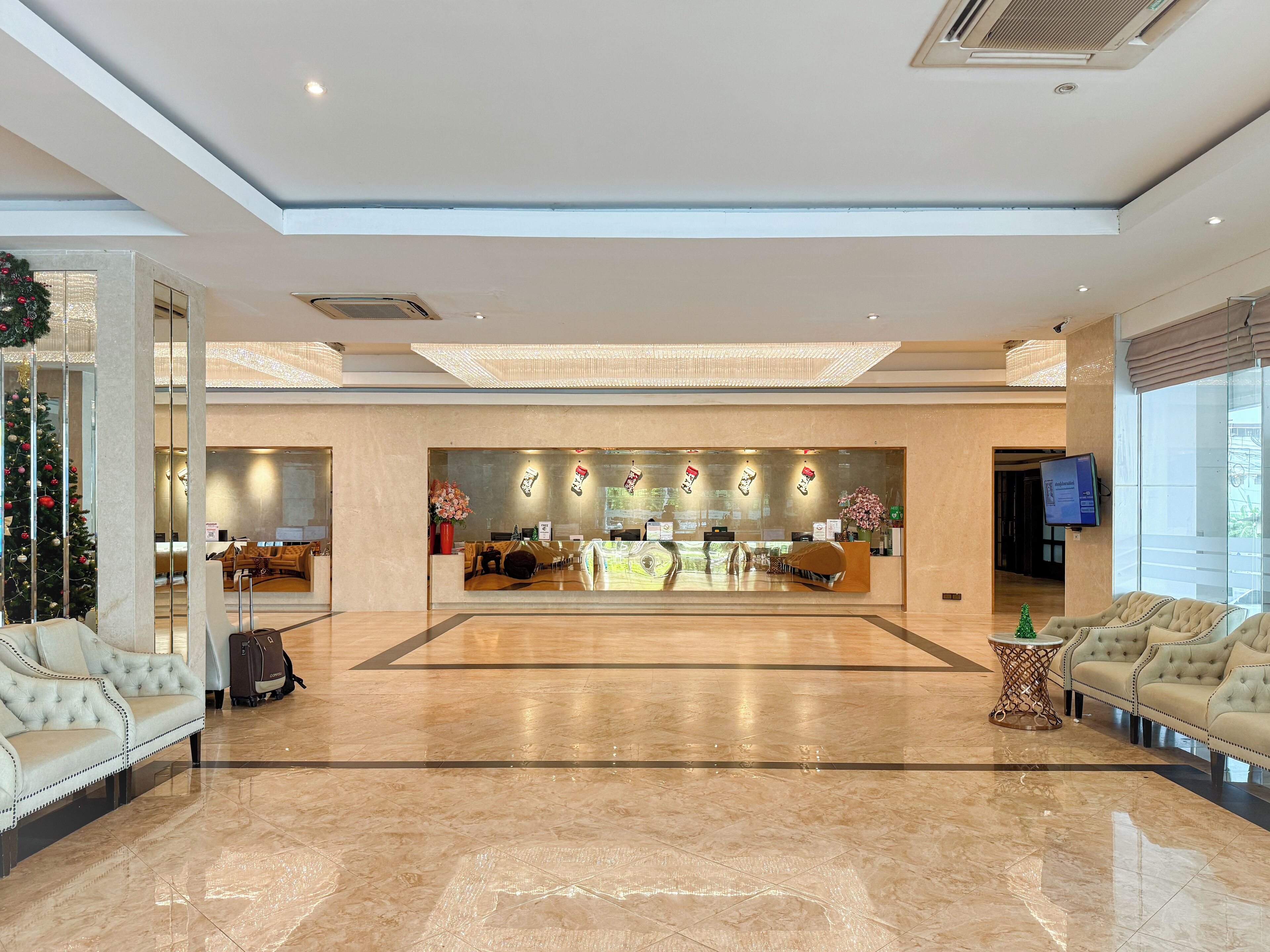 A spacious lobby with a reception desk, seating area, and a Christmas tree.
