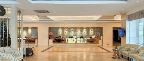 A spacious lobby with a reception desk, seating area, and a Christmas tree.